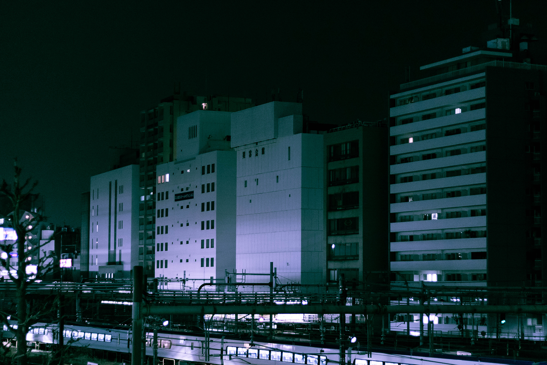 Photograph of a dim set of modern buildings near a city train.